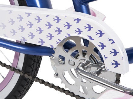 Close-up of the white chain guard with purple bird graphics and matching fenders on the Huffy Good Vibrations cruiser bike. Close-up of the white chain guard with purple bird graphics and matching fenders on the Huffy Good Vibrations cruiser bike.